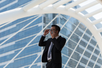 Young Asian businessman sweating due to hot climate. He wiping the face with wet wipes, perspiration, sweat in a city Bangkok Thailand.