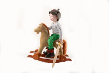 Funny child in old military cap with red star, on toy horse-rocking horse with wooden sword. Boy dreams of battles, victories and adventures. Concept training of spirit, education morale, patriotizm