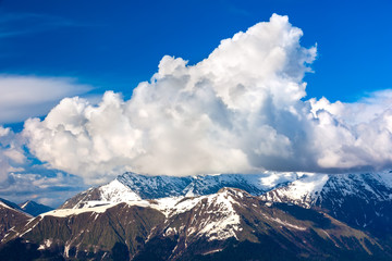 Thawing snow on the top of the mountain ridge in the spring, under the blue sky in the white clouds. Ski Resort at Caucasus Mountains, Rosa Peak, Sochi, Russia.