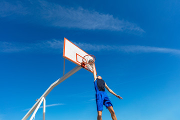 Young Basketball street player making slam dunk