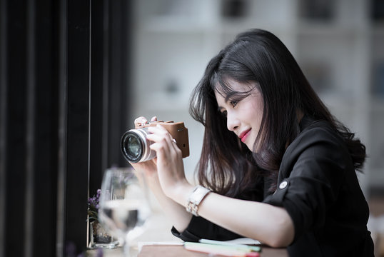 Beautiful woman in black suite holding camera ,looking at screen and taking photos