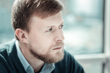 Obraz premium I need to think. Deep calm unshaken man spending time in the bright room looking aside and thinking.