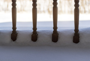 The wooden balusters of the terrace are covered with fresh snow.