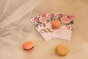 On the wedding invitation lying pastry macaroons and wedding rings. Wedding concept.