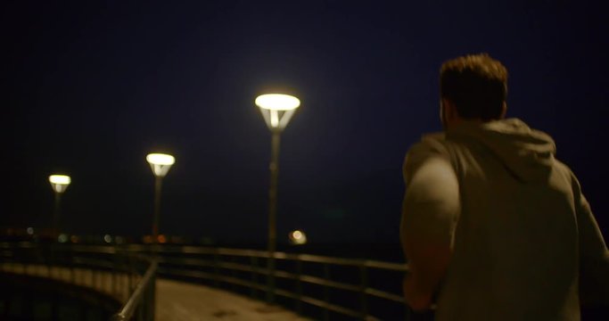 Musuclar young man running on a pier at night
