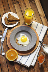 English Breakfast: fried egg, juice, cherry tomatoes, lettuce, grain bread, sauce, top view.