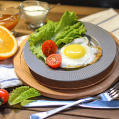 English Breakfast: fried egg, juice, cherry tomatoes, lettuce, grain bread, sauce, top view.