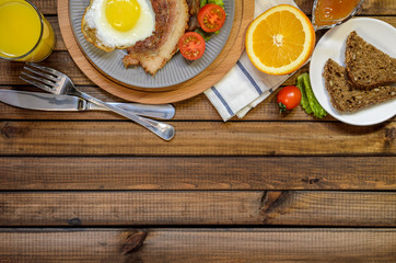 The concept of the English Breakfast: fried egg with bacon, orange juice and vegetables. Free space for text, top view.