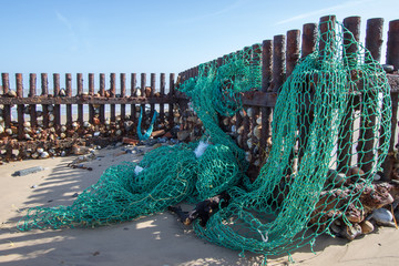Sea fishing net washed up on the beach. Ocean pollution.