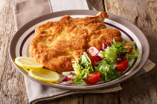 Authentic Italian food: veal Milanese with lemon and fresh vegetable salad close-up. horizontal