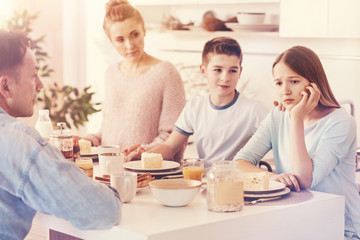 Why are you so sad. Kind boy putting his hand on the shoulder of his sister while supporting her and asking to be happier