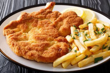 Milanese Beef cutlet breaded with lemon and French fries close-up. horizontal