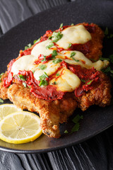 Veal Milanesa Napolitana with mozzarella cheese and tomato sauce close-up on a plate. vertical