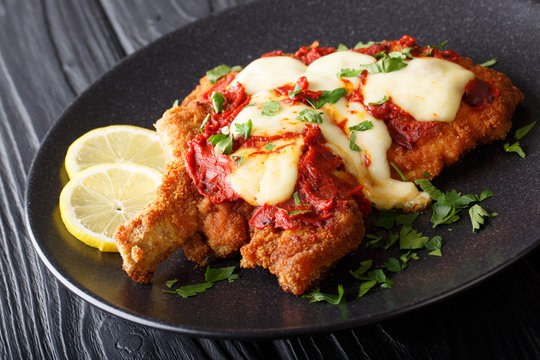South American food: Milanesa napolitana Beef cutlet in breadcrumbs with mozzarella cheese and tomato sauce close-up. horizontal