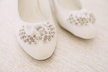 Elegant women's wedding shoes with rhinestones on a light background, the fees of the bride, selective focus