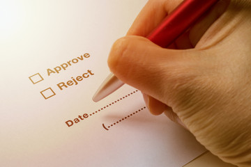 Hand Holding Pen to Sign on Approve or Reject on Document