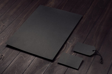 Blank black letterhead, label, business card on dark wood board. Mock up for branding, business presentations and portfolios.