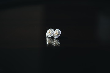 Women's wedding earrings on a black background, selective focus