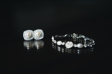 Womens wedding Bridal jewelry set (bracelet and earrings) over black background, selective focus