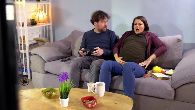 Pregnant woman starting to feel contractions on sofa husband scared