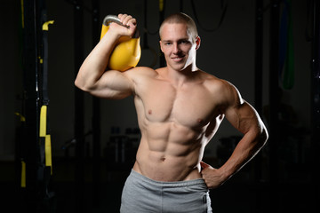 Fototapeta na wymiar Handsome young man working out in gym kettlebell..