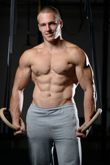 Fototapeta na wymiar Handsome man athlete training at gymnastic rings