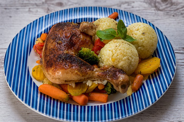 Roasted chicken thigh, vegetables as a supplement, tasty ripe rice with basil, prepared on the table