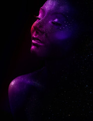 Glowing neon makeup with dramatic look in his eyes. Creative body art on the theme of space and stars. Amazing close-up portrait  glow in the dark makeup.