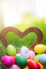 Colorful Easter eggs in a basket on green grass field 
