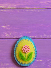Decorative felt Easter egg ornament isolated on a wooden background with copy space. Fun handmade Easter sewing crafts for kids. Happy Easter greeting card. Felt spring crafts