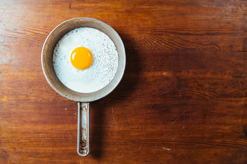 Fresh fried egg/ omelette in a pan on wooden background