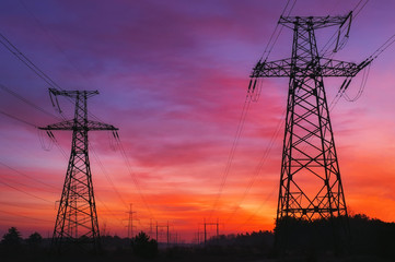 Fototapeta premium High-voltage power lines during fiery sunrise