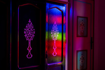 Floral decoration on old Moroccan wooden locker illuminated with red, green and blue light