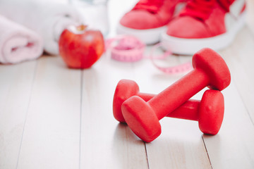 Fitness, healthy and active lifestyles Concept, dumbbells, sport shoes, bottle of waters and apple on wood background.