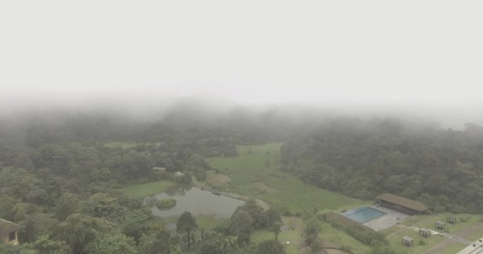 A slow motion aerial view of a landscape amidst mist and passing clouds.