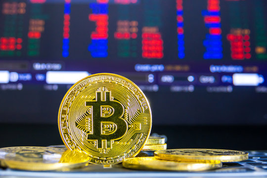 Bitcoins digital money on laptop keyboard with stock exchange market chart background. Virtual cryptocurrency concept.