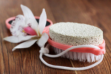 Pink pumice for female feet and orchid on wooden background