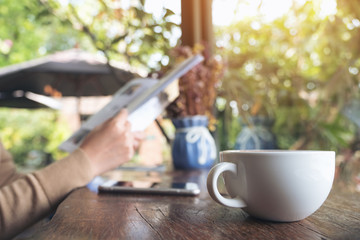 Closeup image of a woman reading book and drinking coffee in cafe