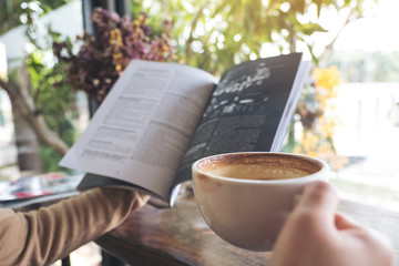 Closeup image of a woman reading book and drinking coffee in cafe