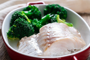 Fish cod baked in the oven with broccoli - healthy diet healthy food. Rustic wooden brown background, side view, selective focus, close up.