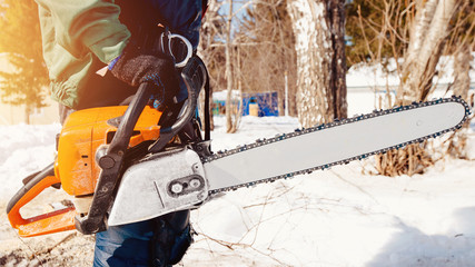 Chainsaw. Close-up of man lumberjack holding chainsaw for cutting down trees.