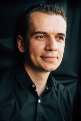 Obraz premium Cute young man in black shirt in studio over black background.
