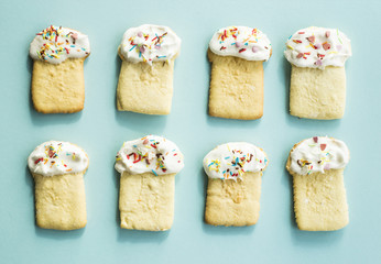 Cookies in the form of Easter cakes, decorated with white icing and colorful sprinkling..On blue background