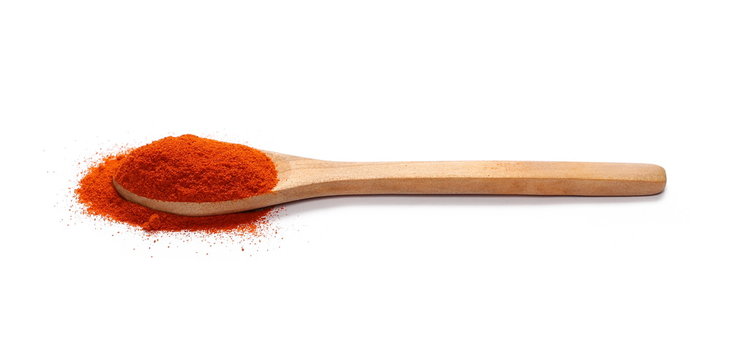 Pile of red paprika powder in wooden spoon isolated on white background