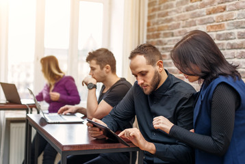 Group of successful young men and women working together in the office. Team of programmers looking for creative decision directing by female team leader.