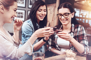 Best friends. Delighted positive female friends laughing and drinking alcohol while meeting together at the pub