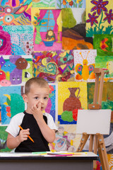 Fototapeta premium Little artist. Colorful wall with paintings in background.