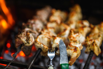 grilled beef meat on the grill with fork and knife close up, barbecue, shashlik, kebab, skewer on the grill
