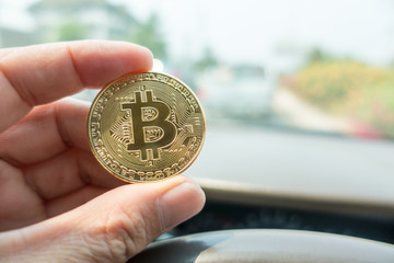 Businessman Holding Golden Bitcoin in car on traffic background. Digital Money and Bitcoine Concept for exchange .