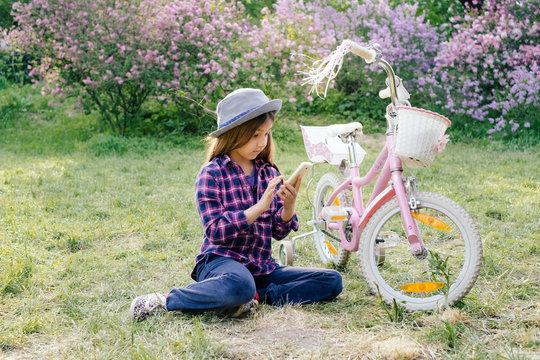 Adorable pre-teen tweenie brunette kid girl with her smartphone in the spring park